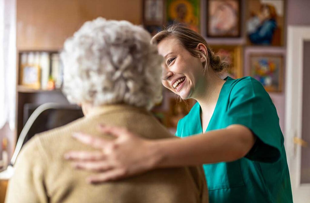 Elderly woman smiling and engaging in a group activity with other residents in a comfortable common room.
