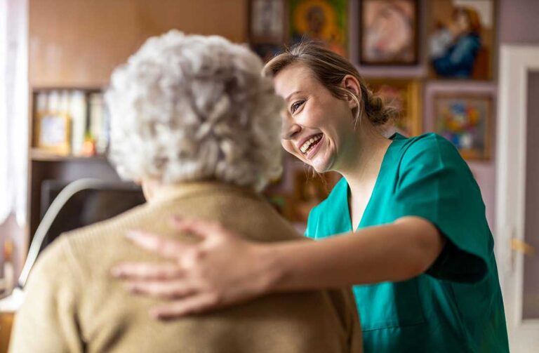 Elderly woman smiling and engaging in a group activity with other residents in a comfortable common room.